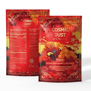 May include: Two red pouches of "Cosmic Dust" by Ox, featuring a fiery design with stars and swirls. The front pouch reads "Fire, Blazing Blood Orange & Chili Sugar." The back pouch displays nutrition facts.