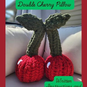May include: Two red, plush cherry pillows with green stems and leaves. Each cherry has a white accent. The image includes the text "Double Cherry Pillow" and "Written Instructions and Photo Guide".