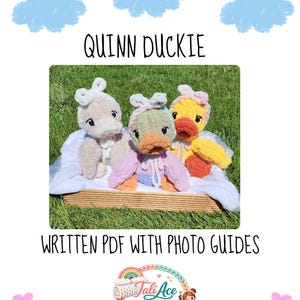 Op de afbeelding: Drie pluche eendjes met het label QUINN DUCKIE, WRITTEN PDF WITH PHOTO GUIDES. De eendjes zijn beige, saliegroen met paars, en geel met oranje, elk met een witte of pastelkleurige hoofdband. Ze zitten in een mandje op het gras.