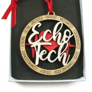 以下が含まれることがあります： 赤いハートと「Echo Tech」という文字が書かれた木製のオーナメント。周囲には、心臓超音波検査技師の資質を表す言葉が円形に並んでいます。