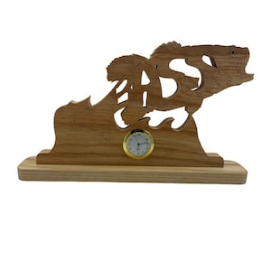 May include: Wooden clock with a bass fish design. The fish is jumping out of the water and the word "BASS" is carved into its body. The clock is on a wooden base.