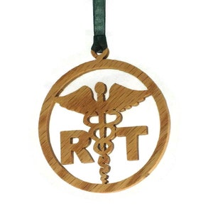 May include: A wooden ornament with a green ribbon. The ornament is round and features a cutout of the medical symbol, a snake wrapped around a staff with wings, and the letters "RT".