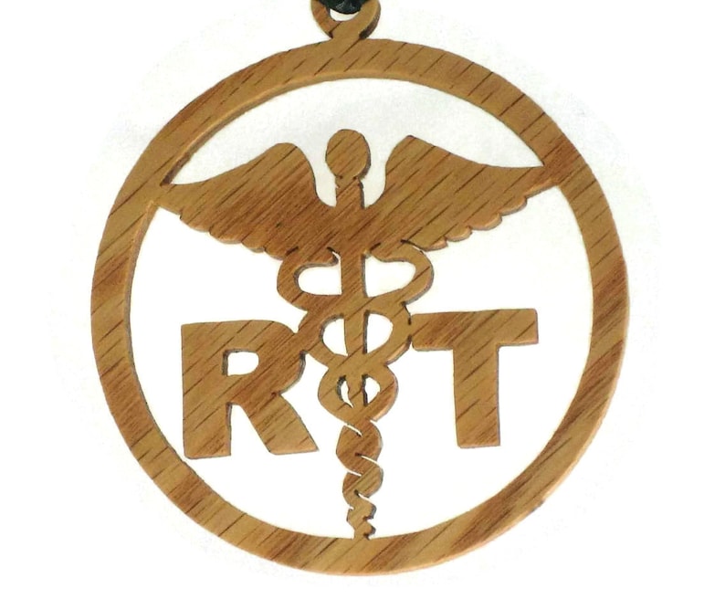May include: A wooden pendant with a medical symbol and the letters "RT" carved into it. The pendant is on a black cord.