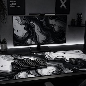May include: A modern black and white computer setup featuring a large monitor, keyboard, mouse, and a patterned mousepad. The desk also includes a gaming PC, headphones, and decorative items. The overall aesthetic is sleek and minimalist.