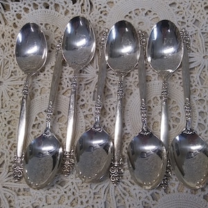 May include: Set of six silver spoons with ornate handles. The spoons have a classic design and are perfect for serving desserts or other dishes.