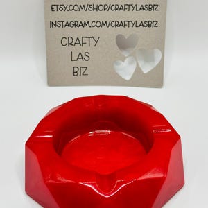 K&ouml;nnte beinhalten: Ein leuchtend roter, facettierter, geometrisch geformter Aschenbecher mit glatter, gl&auml;nzender Oberfl&auml;che. Dahinter befindet sich eine rechteckige, hellbraune Karte mit dem Text "ETSY.COM/SHOP/CRAFTYLASBIZ", "INSTAGRAM.COM/CRAFTYLASBIZ", "CRAFTY LAS BIZ" und drei herzf&ouml;rmigen Ausstanzungen.
