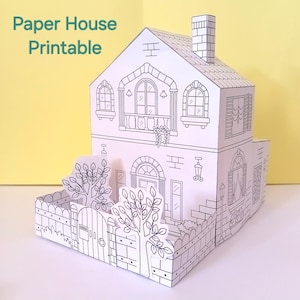 Puede incluir: Una casa de papel imprimible en blanco y negro con el texto "Paper House Printable". La casa presenta elementos arquitectónicos detallados, incluyendo ventanas, un balcón, una chimenea y una valla con árboles.