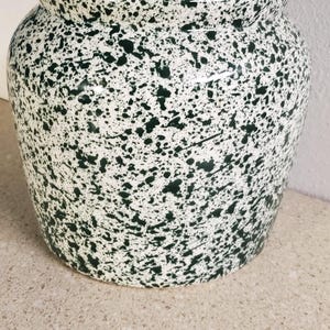 May include: A ceramic jar with a lid, featuring a white base and a speckled green pattern. The jar has a rounded body and a small knob on the lid. The design gives a rustic, handcrafted feel. Ideal for kitchen storage.
