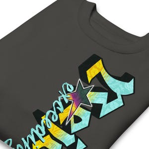 May include: Dark gray sweatshirt with a colorful graphic design. The design features the word "express" in a stylized font, with a star and geometric shapes in yellow, teal, and purple.