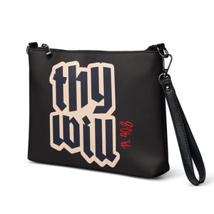 Può includere: Pochette nera con la scritta "thy will" in un carattere audace e stilizzato color crema con contorno nero. Il riferimento biblico "Ps. 40:8" è in rosso. La pochette ha un cinturino da polso.