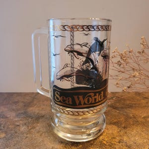 Vintage 1980s Sea World Glass Beer Stein Mug from the Amusement Park. Clear glass with black and gold details. Beautiful Dolphins design