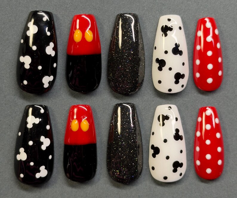 May include: Ten artificial nails in various designs. The designs include black with white polka dots, black with white Mickey Mouse shapes, black with red and yellow Mickey Mouse shapes, black glitter, white with black polka dots, and red with white polka dots.