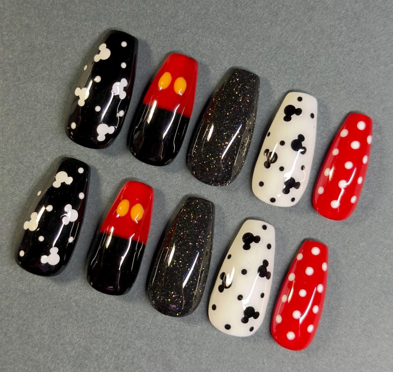 May include: A set of ten artificial nails in various designs. The nails feature black with white polka dots, red with black and yellow accents, black glitter, white with black Mickey Mouse shapes, and red with white polka dots.
