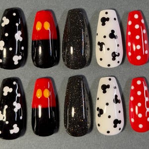 May include: Ten artificial nails in a variety of designs. The nails feature black with white Mickey Mouse shapes, red and black Mickey Mouse designs, black glitter, white with black Mickey Mouse shapes, and red with white polka dots.