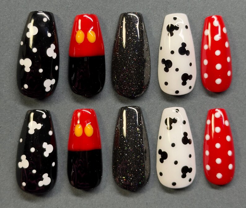 May include: A set of ten artificial nails in various designs. The designs include black with white Mickey Mouse shapes, red with yellow Mickey Mouse ears, black glitter, white with black Mickey Mouse shapes, and red with white polka dots.