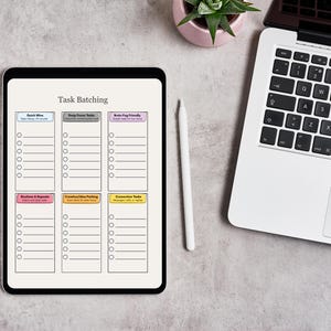 May include: A digital tablet showing a "Task Batching" template, with sections for various task types. A white stylus and a laptop are positioned beside the tablet. A small potted plant is also visible.