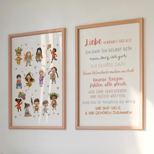 May include: Two framed art prints. One shows diverse cartoon children with hearts. The other has German text: "Liebe verbindet uns alle." Both are in light wood frames, displayed on a white wall.