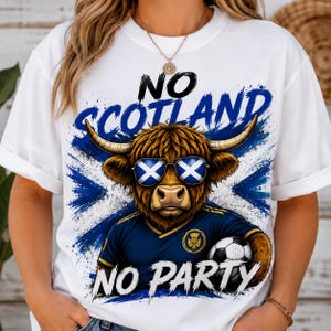 Può includere: Una t-shirt bianca con la grafica di una mucca Highland marrone che indossa occhiali da sole con il motivo della bandiera scozzese. La mucca indossa una maglia da calcio blu e tiene un pallone. Il testo recita NO SCOTLAND NO PARTY su croce blu.