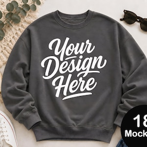 May include: A dark grey crewneck sweatshirt featuring the white text Your Design Here printed in a cursive script font across the centre of the chest. The garment has long sleeves with ribbed cuffs and a ribbed hemline, providing a classic fit.