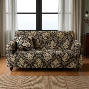 Könnte beinhalten: Ein Zweisitzer-Sofa und ein passendes Kissen mit einem Damastmuster in Schwarz, Beige und Braun. Das Sofa hat ein klassisches Design mit gerollten Armlehnen und einem gerüschten Sockel. Das Kissen ist quadratisch und ergänzt das Muster des Sofas. Das Sofa steht vor einem Fenster.