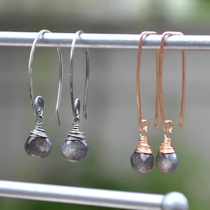 May include: A pair of silver and rose gold dangle earrings with gray gemstone drops.