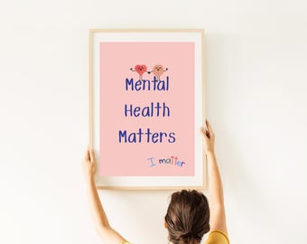 Può includere: Una stampa incorniciata con le parole "Mental Health Matters" in testo blu su sfondo rosa. La stampa include anche la frase "I matter" e due illustrazioni di cuore e cervello. La cornice è marrone chiaro.