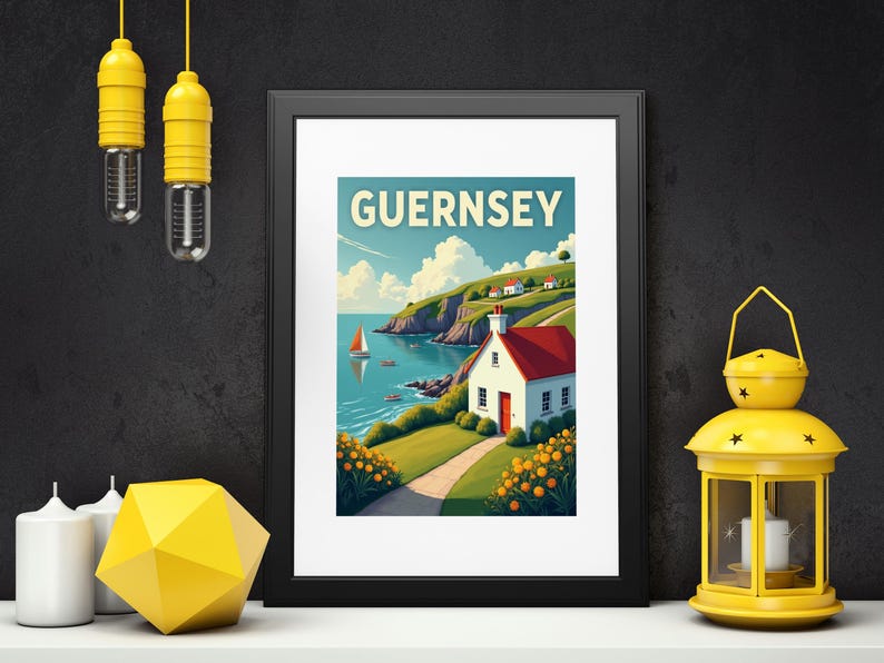 May include: Framed art print featuring a coastal scene with the word "GUERNSEY" at the top. The artwork depicts a white cottage with a red roof, a sailboat on the water, and a path leading to the house. The print is in a black frame.