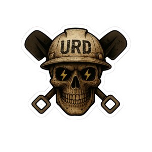 Puede incluir: Una pegatina con una calavera que lleva un casco de construcción con las letras "URD" y palas cruzadas. Los ojos de la calavera están reemplazados por rayos. El diseño tiene un aspecto envejecido y vintage.