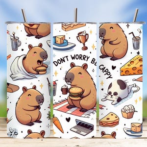 May include: A white tumbler featuring cartoon capybaras with food items like burgers, cheese, and cake. The text "Don't Worry Be Cappy" is also displayed. The design includes a straw and a silver lid.