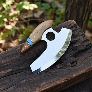 May include: A stainless steel cleaver with a wooden handle. The handle is a light brown color with a blue accent. The cleaver blade is curved and has a circular hole near the handle.