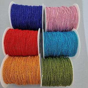 Puede incluir: Seis carretes de cadena metálica en varios colores, incluyendo azul, rosa, rojo, dorado y verde. La cadena está enrollada alrededor de carretes blancos.