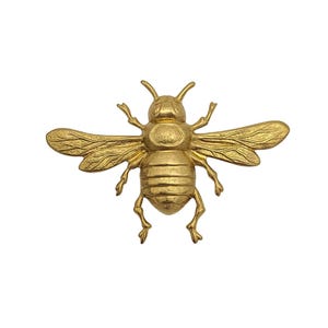May include: A gold-colored bee-shaped decorative object with outstretched wings. The bee has detailed wings, legs, and antennae. The object is likely made of metal and is designed to be a decorative accent.