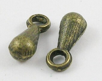 May include: Two antique gold-toned metal teardrop-shaped charms with a loop at the top. The charms have a textured surface.