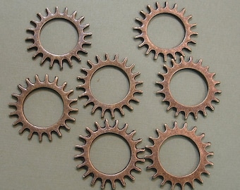 May include: Seven copper-colored metal gears with a sunburst design. Each gear has a circular opening in the center.