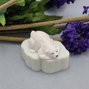 Könnte beinhalten: Eine weiße Eisbärenfigur, die auf einer weißen Eisscholle schläft. Die Figur ist aus Kunststoff und hat ein realistisches Aussehen.