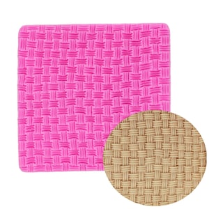 May include: A pink silicone mold with a woven basket weave pattern. A circular inset shows a similar pattern in a tan color. The mold is square with rounded corners, designed for crafting or baking.