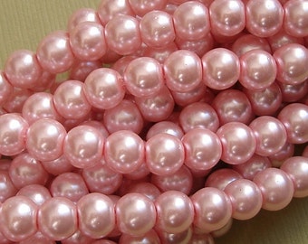 May include: A strand of pink pearl beads. The beads are round and have a smooth, glossy finish.