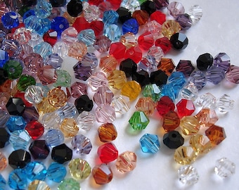 May include: Assortment of colorful faceted glass beads in various shades of red, blue, green, purple, and clear. The beads are small and have a faceted, diamond-like shape.