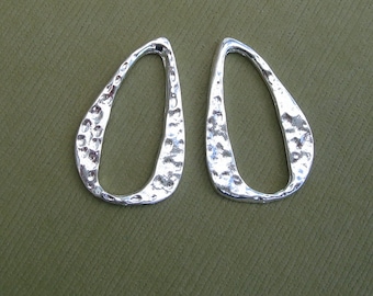 Puede incluir: Un par de pendientes de plata con textura martillada y forma ovalada.