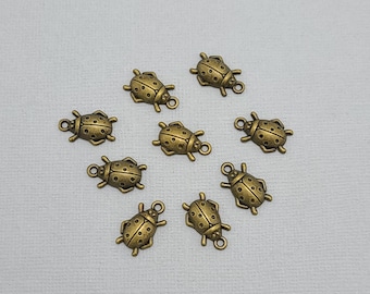 May include: Ten antique gold-toned ladybug charms with black spots. Each charm has a loop for attaching to jewelry or other crafts.