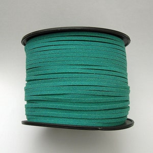 May include: A spool of teal colored suede cord, wound tightly on a black plastic spool.