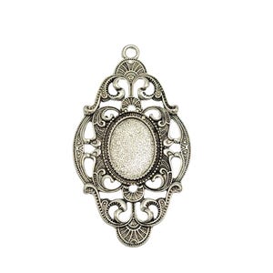 May include: Silver pendant with an ornate design and a blank oval cameo. The pendant has a filigree design with a loop at the top for hanging.