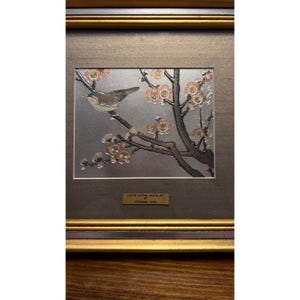 May include: A framed limited edition Chokin art piece featuring a metallic silver background with a dark grey bird perched on a branch with pink and gold-toned plum blossoms. A small gold plaque at the bottom reads: LIMITED EDITION CHOKIN ART BY TOSHIKAZU HARA.