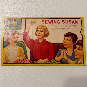 May include: Vintage Sewing Susan card featuring illustrations of women. The card has the text "SEWING SUSAN" and "50 GOLD EYE NEEDLES WITH THREADER". The card has a yellow border and a retro design.