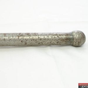 May include: A close-up of a silver metal rod with a rounded end. The rod is slightly rusted and has a worn finish.