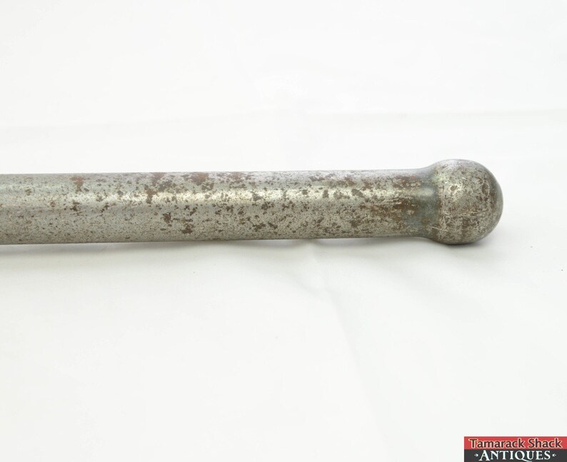 May include: A close-up of a silver metal rod with a rounded end. The rod is slightly rusted and has a worn finish.