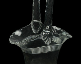 May include: A clear glass basket with a twisted handle. The basket has a scalloped rim and a textured base.