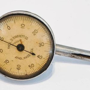 May include: A silver dial gauge with a black needle and a white face. The gauge is labeled "The L.S. Starrett Co. Athol, Mass. USA 1/1000 in".