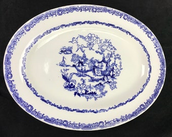 May include: A white oval platter with a blue and white floral design. The design features a pagoda, trees, and birds. The platter has a blue border with a decorative pattern.