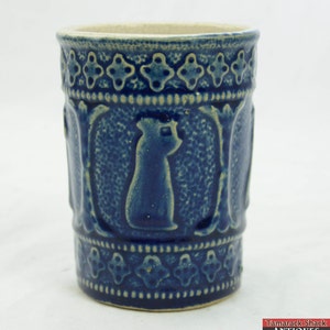 May include: A blue and white ceramic mug with a raised design of a bird. The mug has a white rim and a blue glaze.